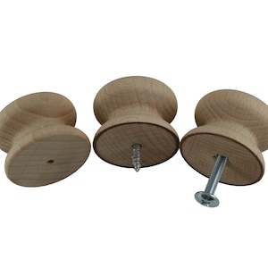 May include: Three wooden knobs with a screw attachment. The knobs are light brown and have a rounded shape.