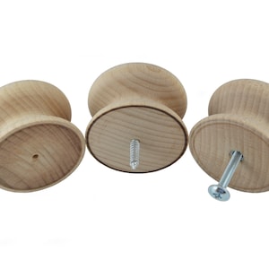 May include: Three wooden knobs with a screw hole in the bottom. The knobs are light brown and have a smooth, rounded surface.
