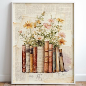 Può includere: Una stampa incorniciata con un'illustrazione ad acquerello di libri antichi con fiori colorati. I libri sono in varie tonalità di marrone e beige, con fiori nei toni del giallo, rosa e bianco. Lo sfondo è un collage di carta invecchiata.
