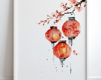 May include: Watercolor print of three red and orange paper lanterns hanging from a flowering branch. The lanterns have intricate floral designs and are set against a white background, framed in a white border.