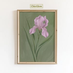 Könnte beinhalten: Gerahmter Druck mit einer detaillierten Illustration einer hellvioletten Irisblüte mit grünen Blättern vor einem gedämpften grünen Hintergrund. Das Kunstwerk ist in einem hellbraunen Holzrahmen eingefasst. Der Text "ChicGlow" befindet sich oben mittig.