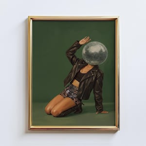 May include: Framed artwork featuring a person with a disco ball for a head, wearing a black leather jacket, black top, and patterned shorts. The person is kneeling on a green background, with one arm raised. The frame is gold.