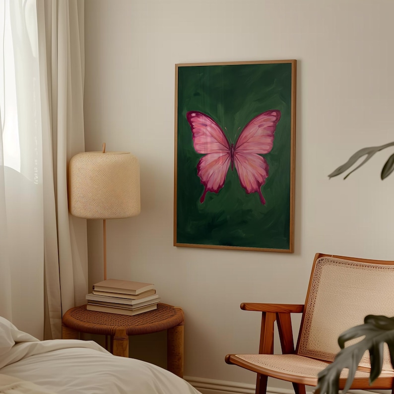 May include: A framed artwork featuring a pink butterfly against a dark green background. The butterfly has detailed wing patterns and is the focal point of the painting. The artwork is displayed in a room with a neutral color palette.