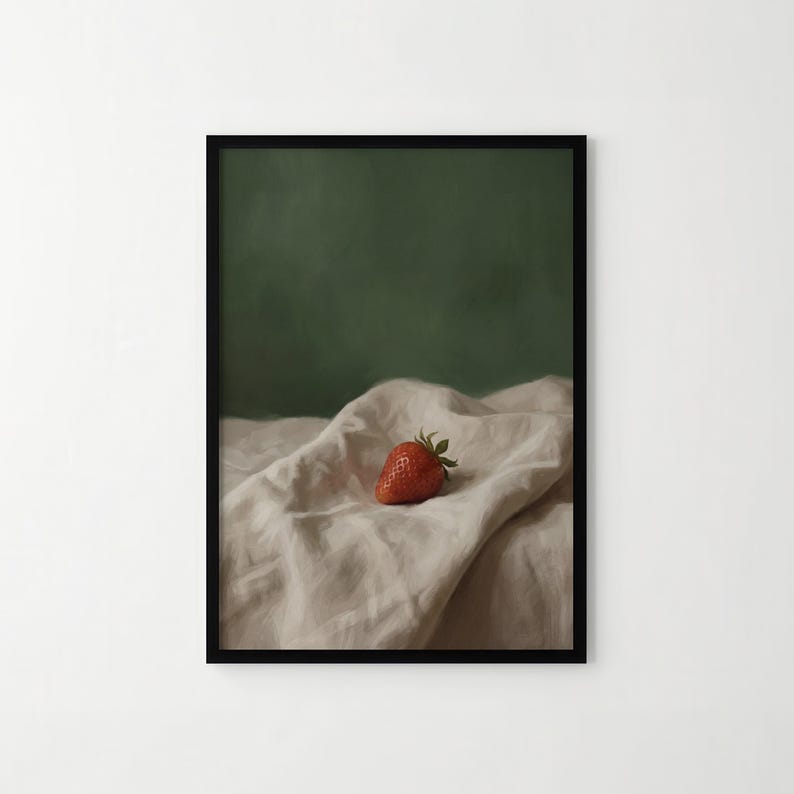 Puede incluir: Una impresi&oacute;n art&iacute;stica enmarcada que presenta una fresa madura. La fruta roja se encuentra sobre una tela beige texturizada, con un fondo verde oscuro. La obra de arte tiene una calidad suave y pict&oacute;rica, evocando calma y simplicidad.