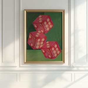 May include: A framed artwork featuring three red dice with white dots against a green background. The dice are arranged in a dynamic composition, with a gold frame. The artwork is displayed on a white wall.