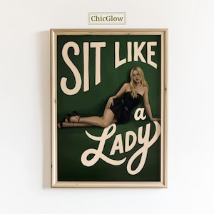 Könnte beinhalten: Ein gerahmter Kunstdruck mit dem Text "SIT LIKE a LADY" in weißer Schrift auf einem dunkelgrünen Hintergrund. Das Kunstwerk zeigt eine Frau in einem schwarzen Kleid. Der Rahmen ist hellbraun, und der Markenname "ChicGlow" befindet sich oben links.