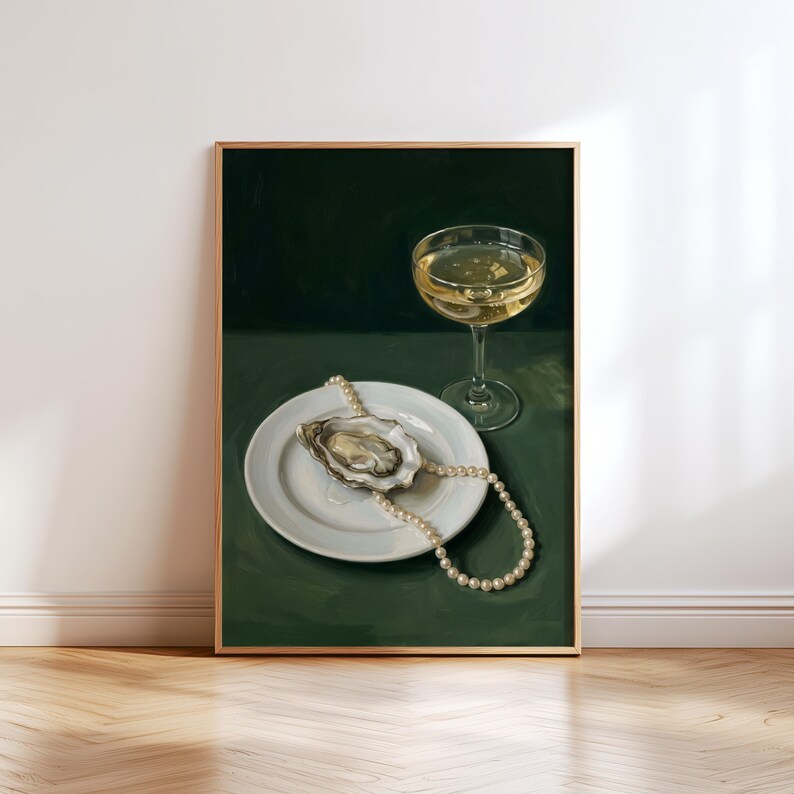 May include: A framed print featuring a still life composition. A white plate holds an oyster with a pearl necklace draped over it. A champagne glass with a golden liquid sits beside the plate. The background is a dark green.