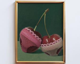 May include: A framed art print featuring two cherries adorned with pink lace lingerie. The cherries are a deep red color, set against a dark green background. The artwork is framed in a gold-colored frame.