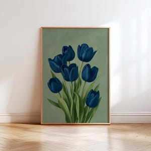 May include: A framed art print featuring a bouquet of deep blue tulips against a muted green background. The flowers have detailed petals and green leaves. The frame is a light gold color, and the artwork is displayed on a white wall above a wooden floor.