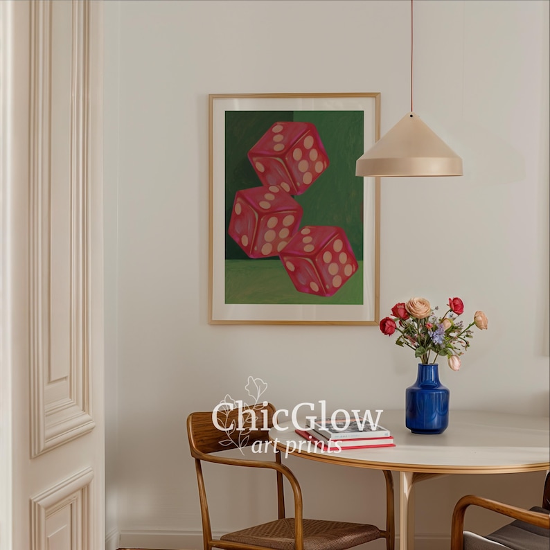 May include: A framed art print featuring three red dice with white dots against a green background. The artwork is displayed in a room with a round table, a blue vase of flowers, and a pendant light.