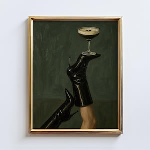 May include: A framed art print featuring a cocktail glass balanced on a black high-heeled boot. The artwork has a dark green background and a gold frame. The image is a stylish and artistic representation of a cocktail.