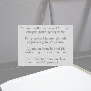 May include: A silver aluminum frame by HALBE featuring a magnetic system and anti-reflective museum glass with 92% UV protection. The text on the frame reads: Aluminum frame by HALBE with a unique magnetic system. Anti-reflective museum glass with 92% UV protection.