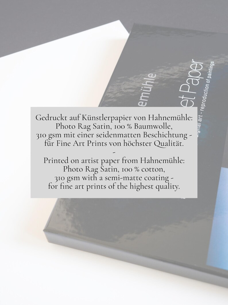 May include: A stack of white and dark gray paper sheets featuring text that reads: Printed on artist paper from Hahnem&uuml;hle: Photo Rag Satin, 100% cotton, 310 gsm with a semi-matte coating - for fine art prints of the highest quality.