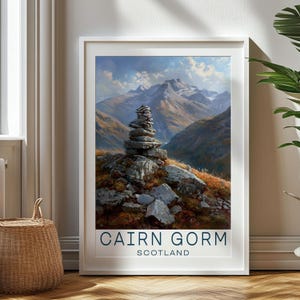 May include: A framed print of a mountain landscape with a stone cairn in the foreground. The print features a blue sky with white clouds and a mountain range in the background. The text "CAIRN GORM SCOTLAND" is printed at the bottom of the print.