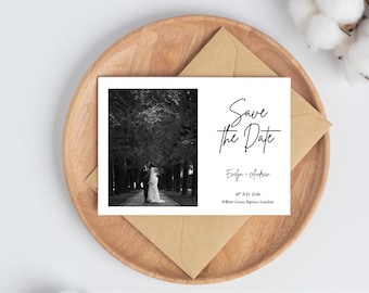 Könnte beinhalten: Eine weiße Save-the-Date-Karte mit einem Schwarz-Weiß-Foto eines Paares. Die Karte mit dem Text „Save the Date“ liegt auf einem Holztablett mit einem braunen Umschlag. Datum und Namen sind ebenfalls aufgedruckt.