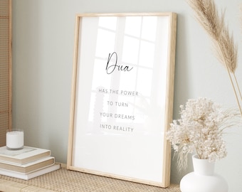 Puede incluir: Una impresión enmarcada con el texto "Dua has the power to turn your dreams into reality" sobre un fondo blanco. La impresión está colgada en una pared sobre un banco de madera con cojines de ratán tejido.