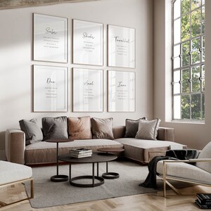 K&ouml;nnte beinhalten: Ein Wohnzimmer-Interieur mit einem Eck-Sofa, einem Couchtisch und einem Sessel. Die W&auml;nde sind mit sechs gerahmten Drucken geschm&uuml;ckt, die islamische Kalligraphie in arabischer Schrift zeigen. Die Drucke sind in einem Raster angeordnet. Der Text auf den Drucken enth&auml;lt die W&ouml;rter "Sabr", "Shukr", "Tawakkul", "Dua", "Amal" und "Iman".