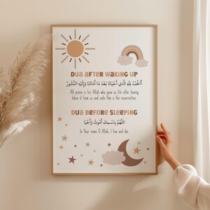 May include: A printable wall art poster with a brown wood frame. The poster features two Islamic prayers in Arabic and English. The top prayer is for waking up and the bottom prayer is for sleeping. The poster is decorated with a sun, rainbow, moon, and stars.