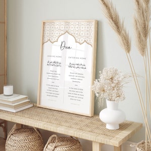 Puede incluir: Una impresi&oacute;n enmarcada con un fondo beige y un patr&oacute;n geom&eacute;trico. La impresi&oacute;n presenta la palabra "Dua" en una fuente decorativa e incluye texto &aacute;rabe y traducciones al ingl&eacute;s para salir y entrar a una casa. El texto dice "Bismillahi walajna, wakala rabbina tawakkalna" y "Bismillahi tuwakkaltu ala Allahi, wa la hawla wa la quwwata illa billah".
