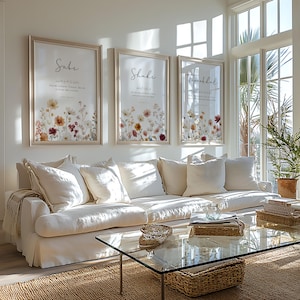 May include: Three framed floral art prints with the words "Sabe", "Shukr", and "Tawakkal" in elegant script. The prints feature a watercolor-style floral design in shades of yellow, orange, and red. The frames are a light wood color.