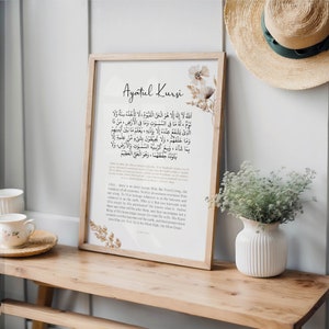 Puede incluir: Una impresi&oacute;n enmarcada con un fondo beige y un dise&ntilde;o floral. La impresi&oacute;n presenta el texto &aacute;rabe de Ayatul Kursi, un vers&iacute;culo del Cor&aacute;n, junto con una traducci&oacute;n al ingl&eacute;s.