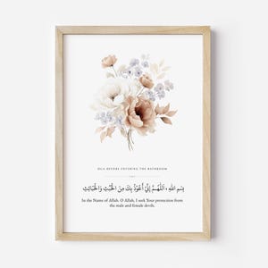 Puede incluir: Una impresión enmarcada con un arreglo floral en acuarela en tonos blancos, melocotón y marrón. La impresión incluye texto árabe y la traducción al inglés: "DUA BEFORE ENTERING THE BATHROOM" y "In the Name of Allah, I seek Your protection from the male and female devils."