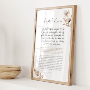 Puede incluir: Una impresi&oacute;n enmarcada con un fondo beige y acentos florales marrones. La impresi&oacute;n presenta el texto &aacute;rabe de Ayatul Kursi, un vers&iacute;culo del Cor&aacute;n, con una traducci&oacute;n al ingl&eacute;s debajo. El marco es de madera con un acabado marr&oacute;n claro.
