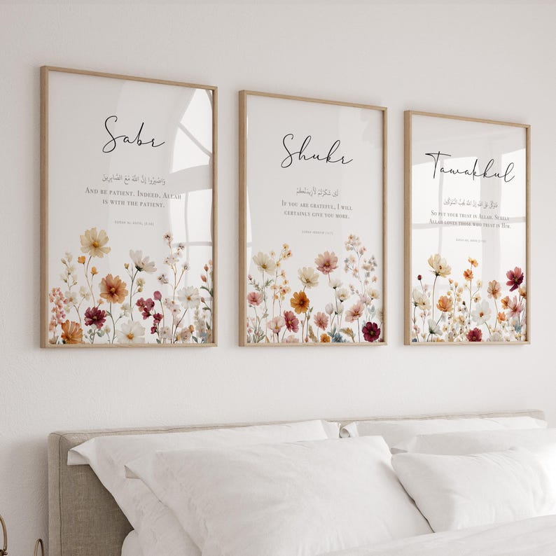 May include: Three framed art prints with floral designs and calligraphy. Each print features a different word: "Saber," "Shukr," and "Tawakkul." The floral arrangements include white, yellow, orange, and burgundy flowers. The frames are a light brown color.