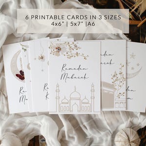 May include: Six printable cards in three sizes: 4x6 inches, 5x7 inches, and A6. The cards feature a beige background with gold and white calligraphy that says "Ramadan Mubarak". The cards also feature a mosque illustration and a floral design.