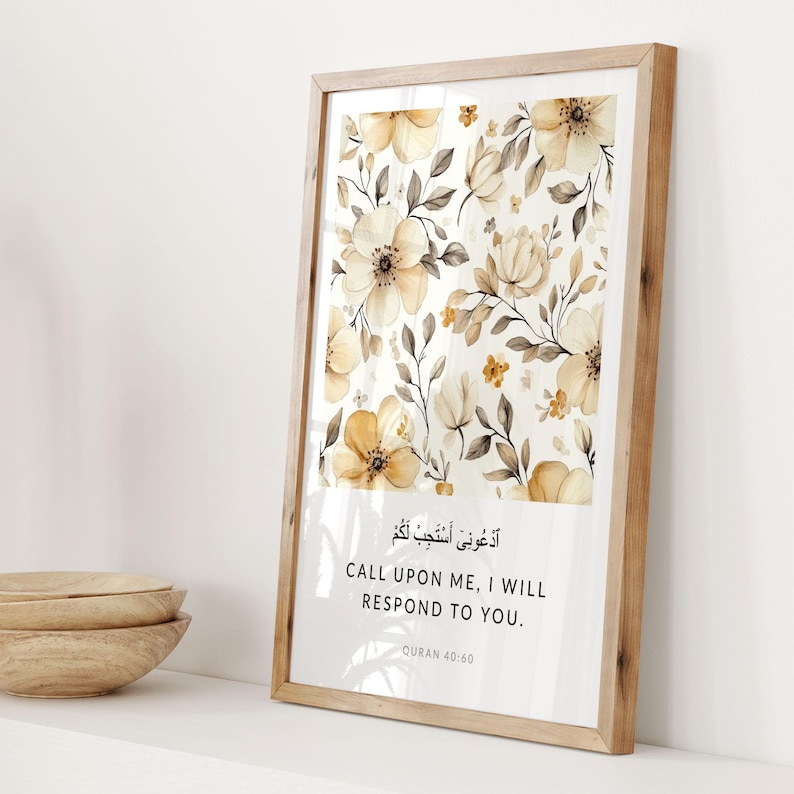 May include: A framed print with a floral pattern in shades of brown and yellow. The print features an Arabic quote in black text that translates to "Call upon me, I will respond to you." The quote is attributed to the Quran 40:60.