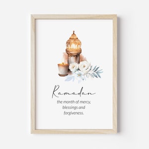 May include: A printable Ramadan art print featuring a gold lantern with a lit candle and white flowers. The text reads "Ramadan, the month of mercy, blessings and forgiveness."