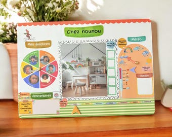 May include: A colorful educational board with French text, featuring sections for emotions, birthdays, and weather. The board has a picture of a play kitchen and a rainbow. The frame is white with red and green accents.