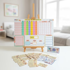 Könnte beinhalten: Eine Belohnungstafel mit der Aufschrift "TABLEAU DE RÉCOMPENSES" auf einer Holzstaffelei, bestehend aus einem Raster mit farbigen Spalten, leeren Feldern und Text. Unter der Staffelei liegen zahlreiche kleine rechteckige Karten mit Illustrationen.