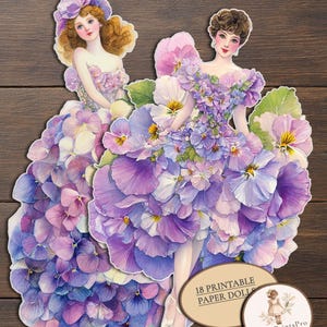 May include: Two paper dolls featuring figures wearing elaborate gowns constructed from layers of purple, violet, and blue pansy petals. A circular label displays the text 18 PRINTABLE PAPER DOLLS and the logo for PaperPrintsPro.
