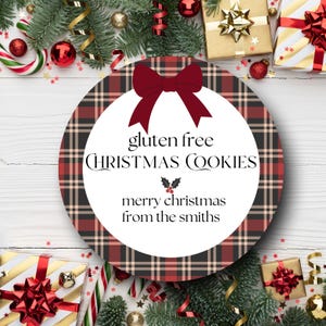 May include: A round Christmas-themed gift tag with a plaid pattern in red, black, and beige. The tag features a burgundy bow and text that reads "gluten free CHRISTMAS COOKIES" and "merry christmas from the smiths". Festive decorations surround the tag.
