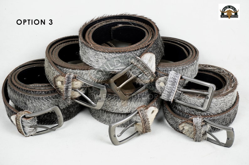 May include: Several rolled leather belts with silver-toned buckles. The belts have a gray and white speckled fur-like texture. The image includes the text "OPTION 3" in the upper left corner and a logo in the upper right corner.