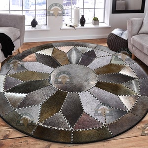 May include: A round, gray and brown patchwork leather rug with a geometric design. The rug is made of different pieces of leather sewn together to create a unique pattern.