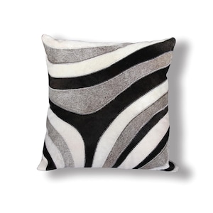 May include: A black, white, and gray patterned throw pillow with a wavy design. The pillow is made of cowhide.