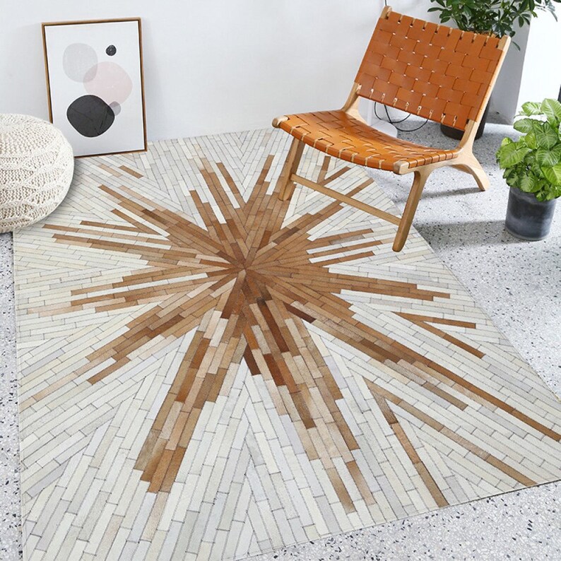 Pu&ograve; includere: Un tappeto geometrico bianco e marrone in pelle. Il tappeto ha un design a stella con un cerchio centrale.