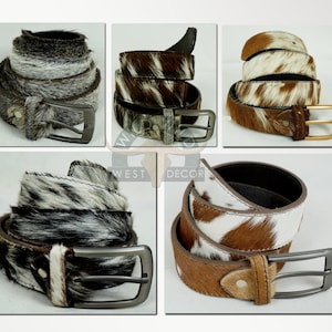 May include: A collection of cowhide belts in various patterns and colors. The belts feature silver and gold-toned buckles. The cowhide patterns include black and white, brown and white, and gray and white.