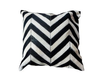 May include: Black and white chevron patterned throw pillow made from cowhide.