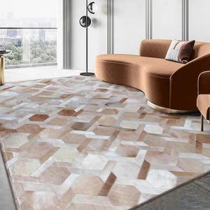 Peut inclure: Un grand tapis à motifs géométriques dans des tons beige et marron. Le tapis est en cuir de vache et présente un design moderne et unique.