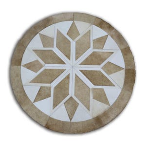 Puede incluir: Alfombra redonda con un diseño geométrico de estrella. La alfombra presenta un patrón de estrella central en tonos beige y blanco, rodeado por un borde de segmentos beige y crema. La alfombra está hecha de un material natural.