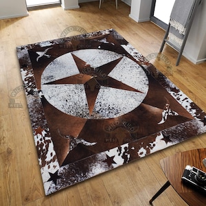 Puede incluir: Una alfombra de piel de vaca marrón y blanca con una gran estrella marrón en el centro. La alfombra está rodeada por un borde de estrellas más pequeñas. La alfombra está sobre un suelo de madera.