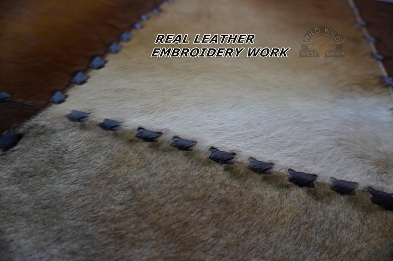 Close-up of a brown, white, and tan leather patchwork rug with black stitching.