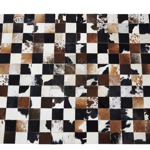 May include: Checkerboard patterned cowhide rug with black, white, brown, and tan squares.
