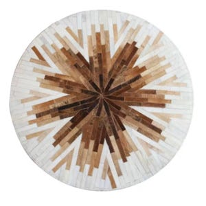 Puede incluir: Una alfombra redonda con un diseño de estrella. Presenta piezas rectangulares en tonos marrones, beige y blancos, dispuestas en un diseño radial. La alfombra parece estar hecha de materiales naturales, posiblemente piel o cuero, y es adecuada para un espacio habitable.