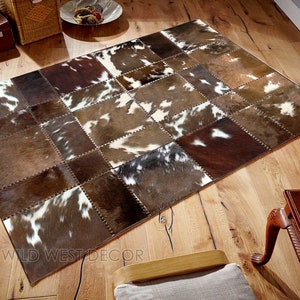 Peut inclure: Un tapis en peau de vache patchwork avec des patchs bruns, blancs et noirs. Le tapis est fait de vraie peau de vache et a un style rustique et western.