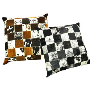 Könnte beinhalten: Zwei dekorative Kissen mit Patchwork-Muster aus Kuhfell. Die Kissen sind schwarz, weiß und braun.