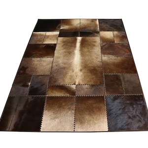 A patchwork cowhide rug with brown and tan squares. The rug is made of real cowhide and has a natural, rustic look.